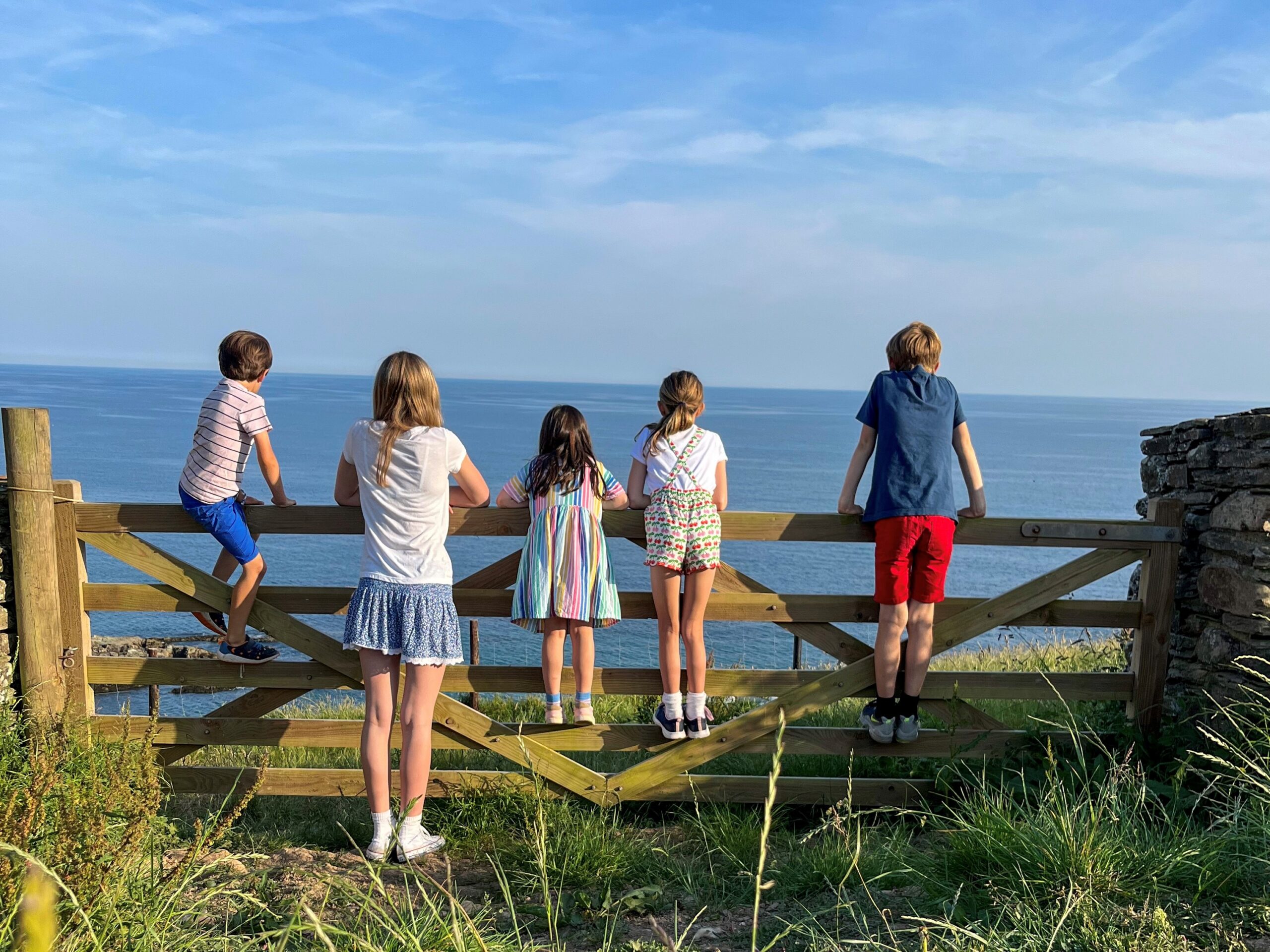 children stood by the gate looking out to sea